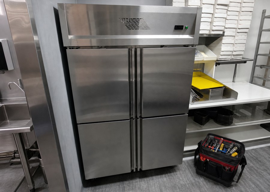 Upright commercial fridge repaired in a food-service setting